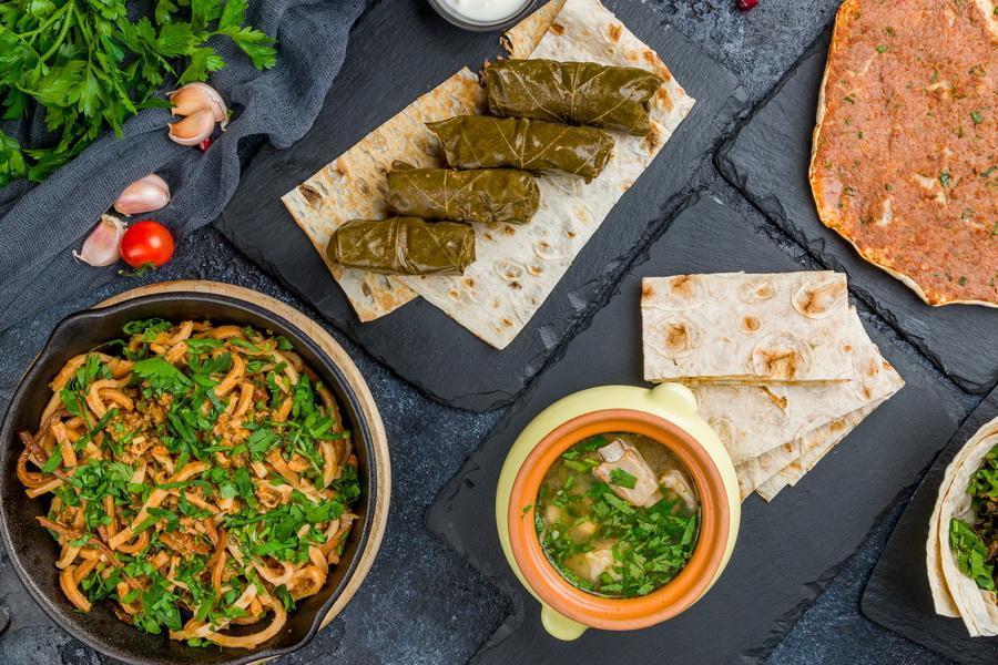 Armenian cuisine food set. Aveluk, dolma , lahmacun, Armenian cuisine on black stone table top view.